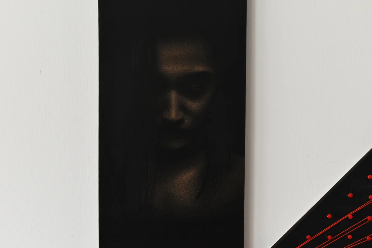 EGO installation view with a dark face and a black panel crossed by red lines
